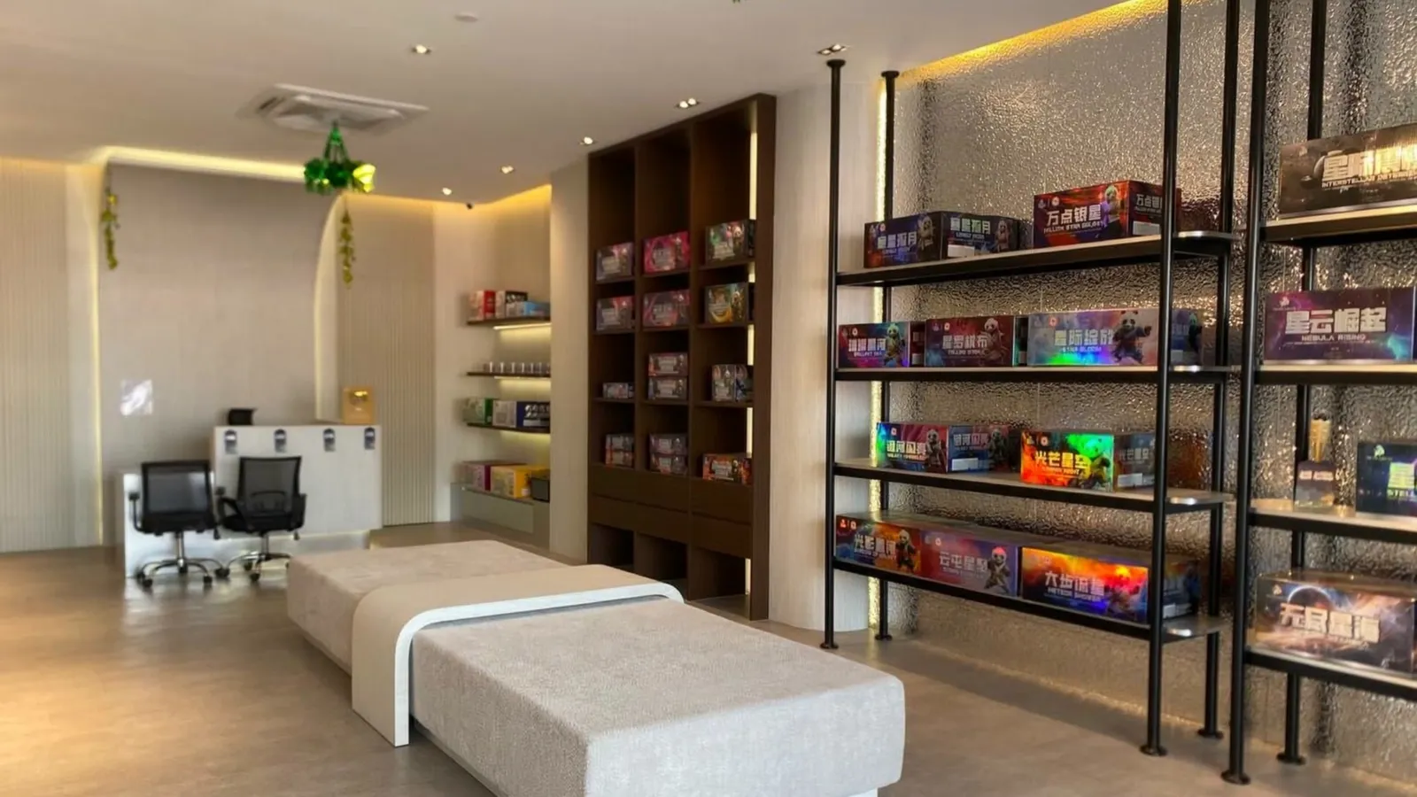 The Bangi showroom: dark timber shelving stacked with boxed fireworks down one wall, a lit display shelf opposite and a pale bench between them.