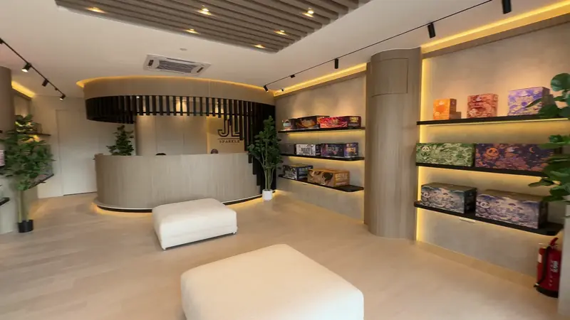 The Nilai showroom seen from the door: a curved counter at the far end, a long white bench, and lit shelves of printed cartons down both sides.
