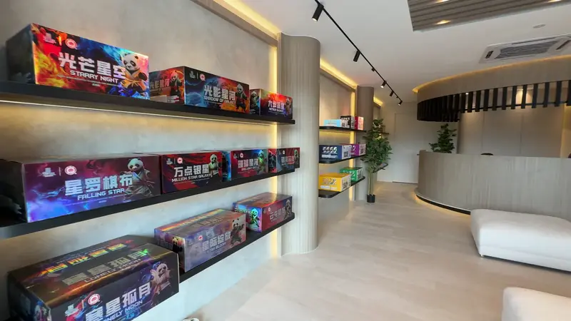A lit shelf wall at Nilai carrying printed cartons in rows, with the counter and a plant at the end.