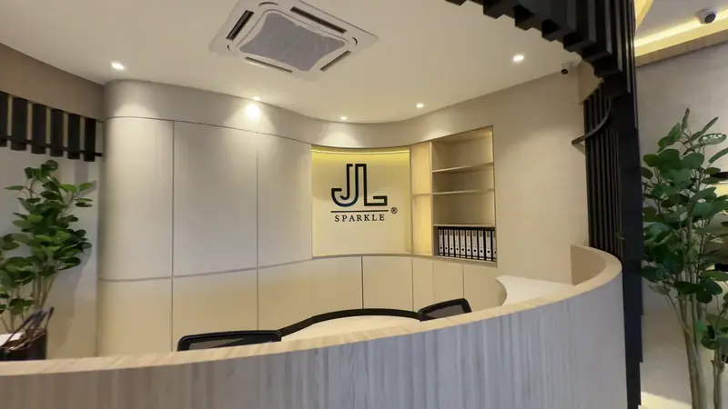 The Nilai showroom counter, curved and pale, with the JL SPARKLE mark on the wall behind it.